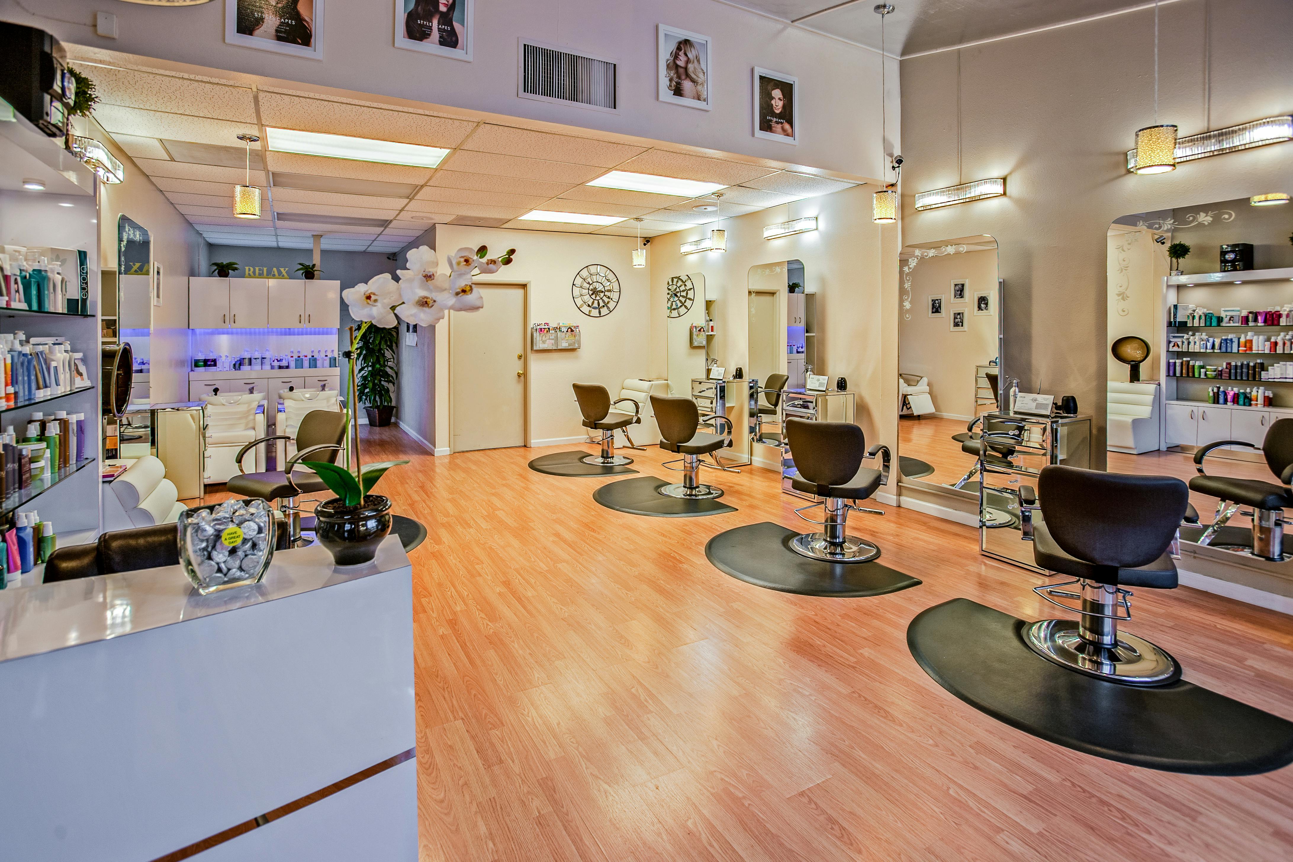 Bright elegant salon interior with styling chairs, mirrors, and orchid flowers at Luxe Hair Studio