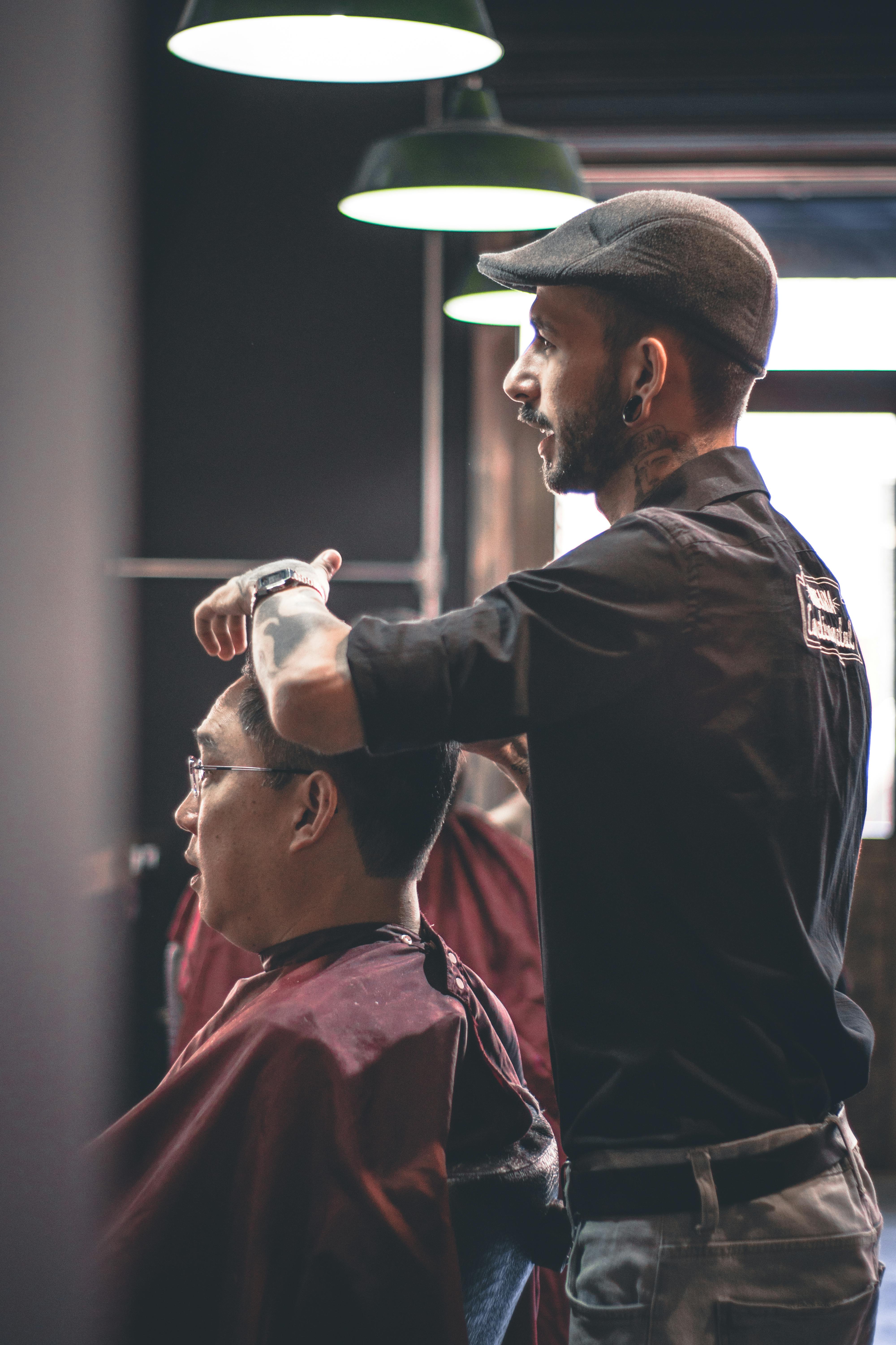 Professional barber styling a client's hair under industrial pendant lights at Sharp Cuts Barbershop
